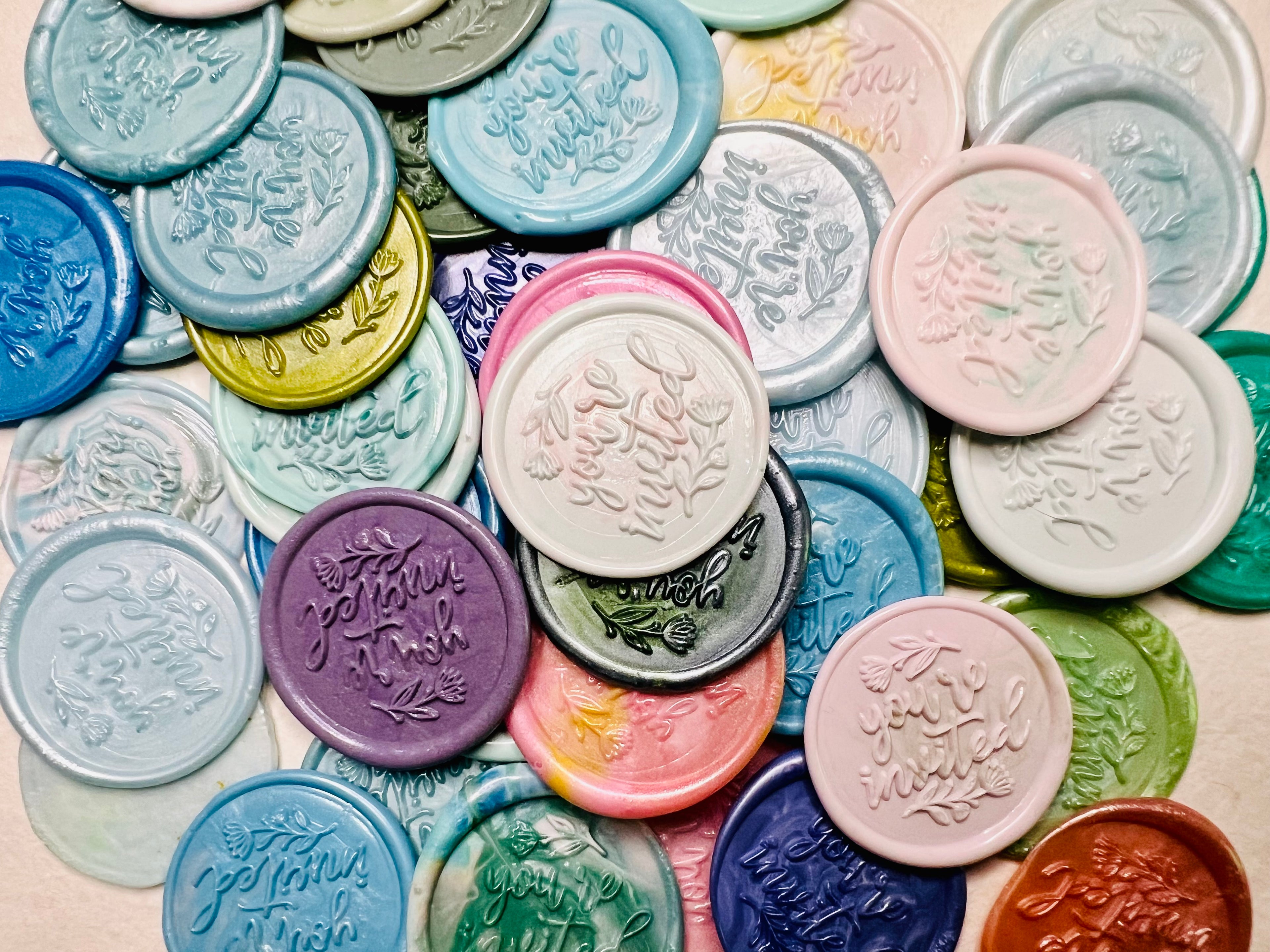 Overhead view of the Handcrafted “You’re Invited” wax seal stickers in various colors