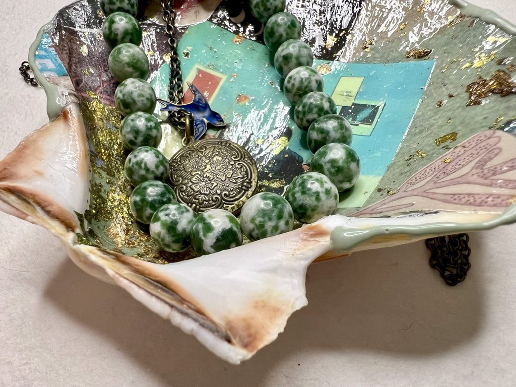 Decorative scallop shell dish with green tones and metallic accents