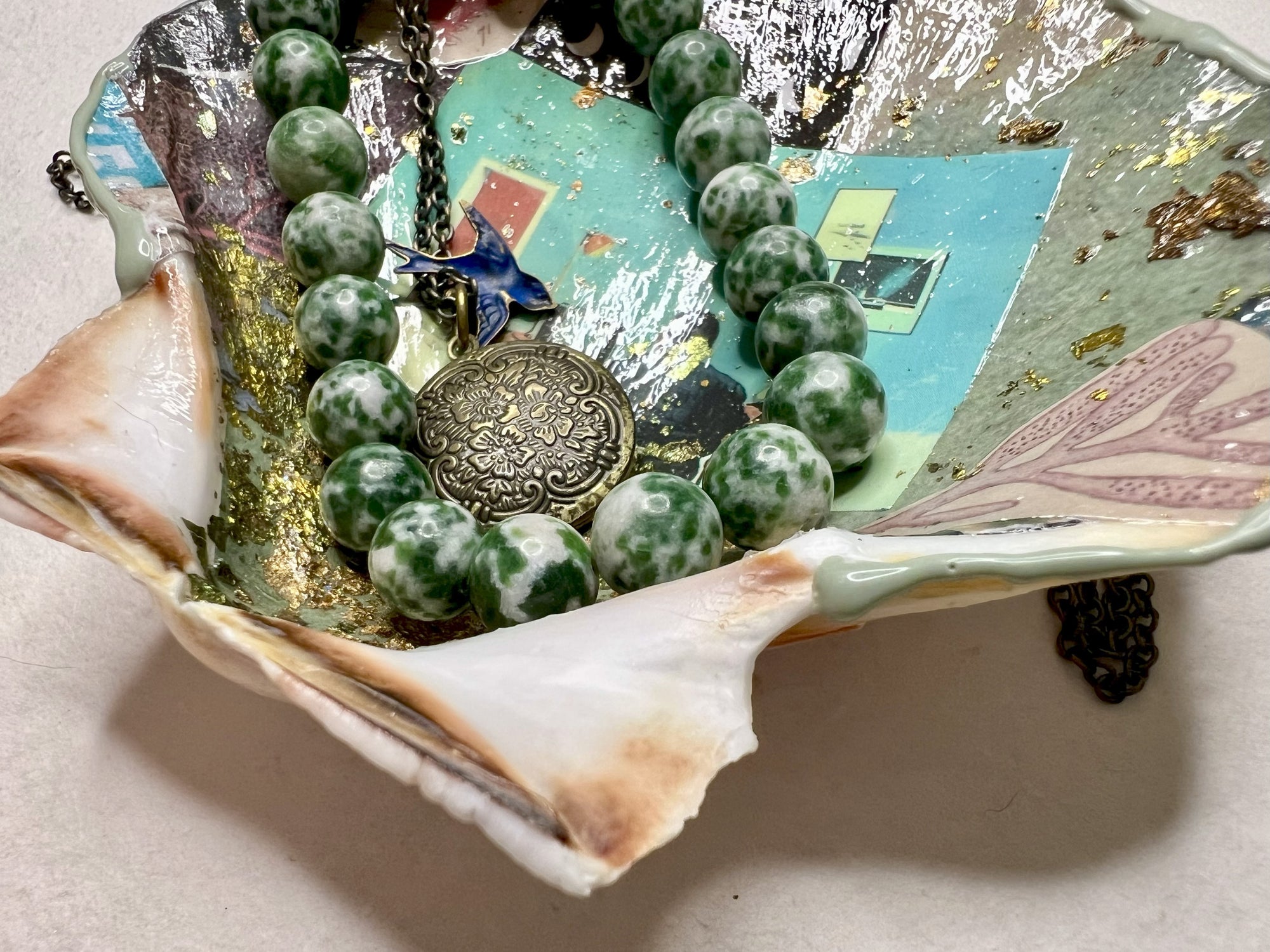 Decorative scallop shell dish with green tones and metallic accents