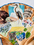 Vintage-inspired collage shell dish with imagery of sea creatures, shells, lunar phases, and a graceful heron
