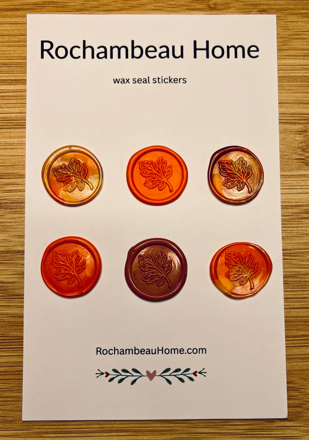 Packaging of Rochambeau Home Falling for You Maple Leaf Wax Seal Stickers with maple leaf designs on a wooden surface.