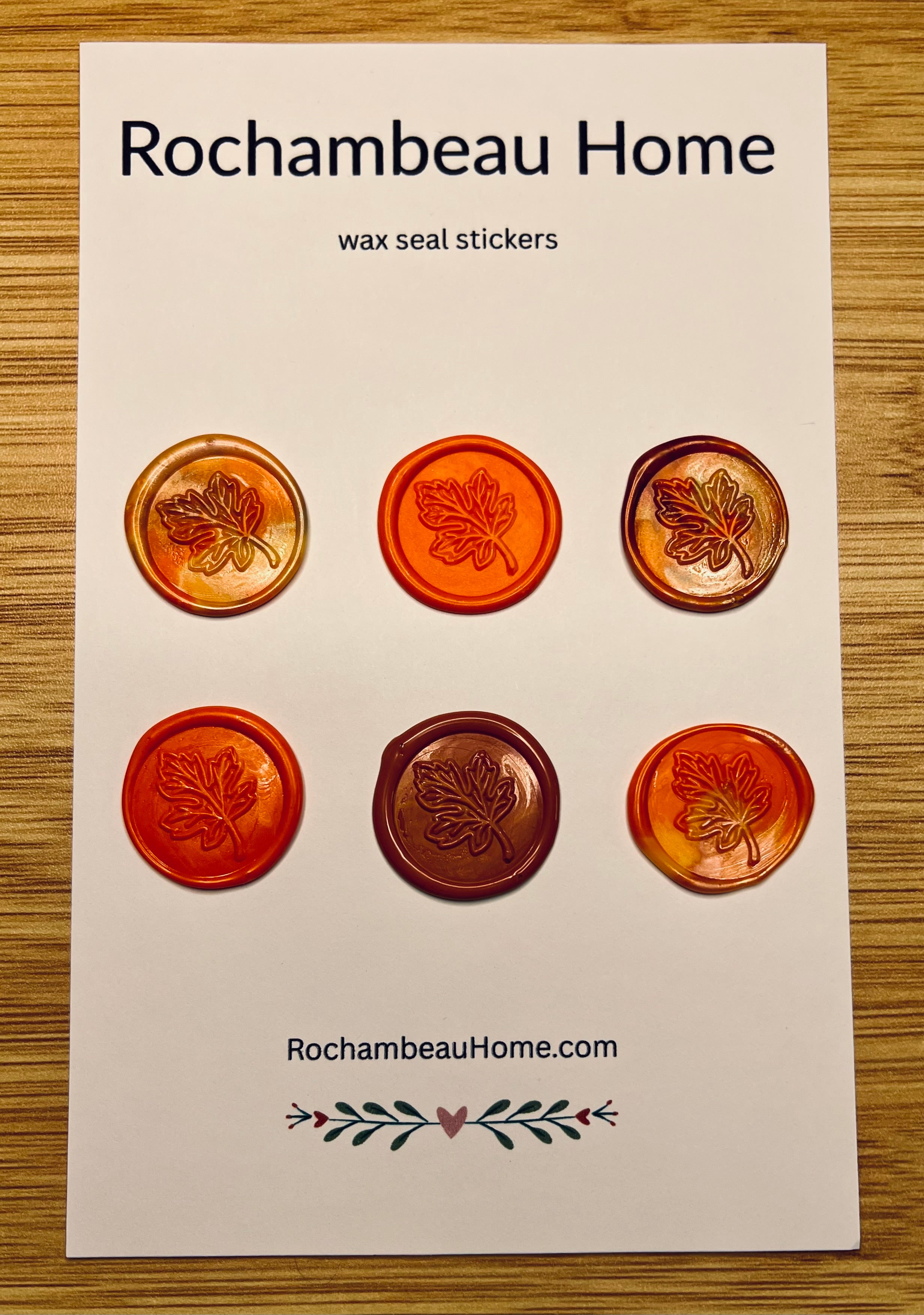 Packaging of Rochambeau Home Falling for You Maple Leaf Wax Seal Stickers with maple leaf designs on a wooden surface.