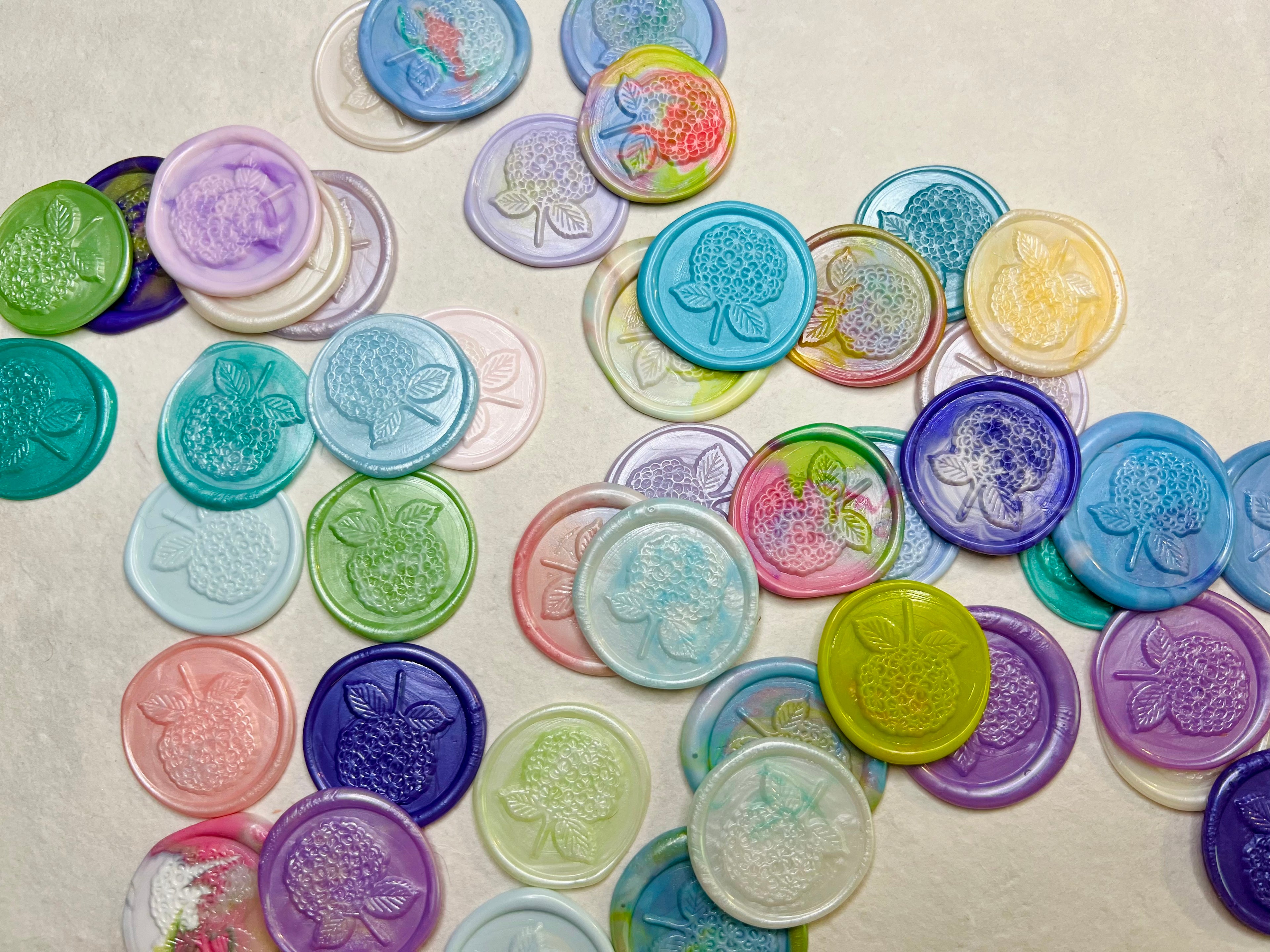 Hydrangea Bloom Wax Seal Stickers laid out on natural handmade paper showcasing the vibrant colors of the seals