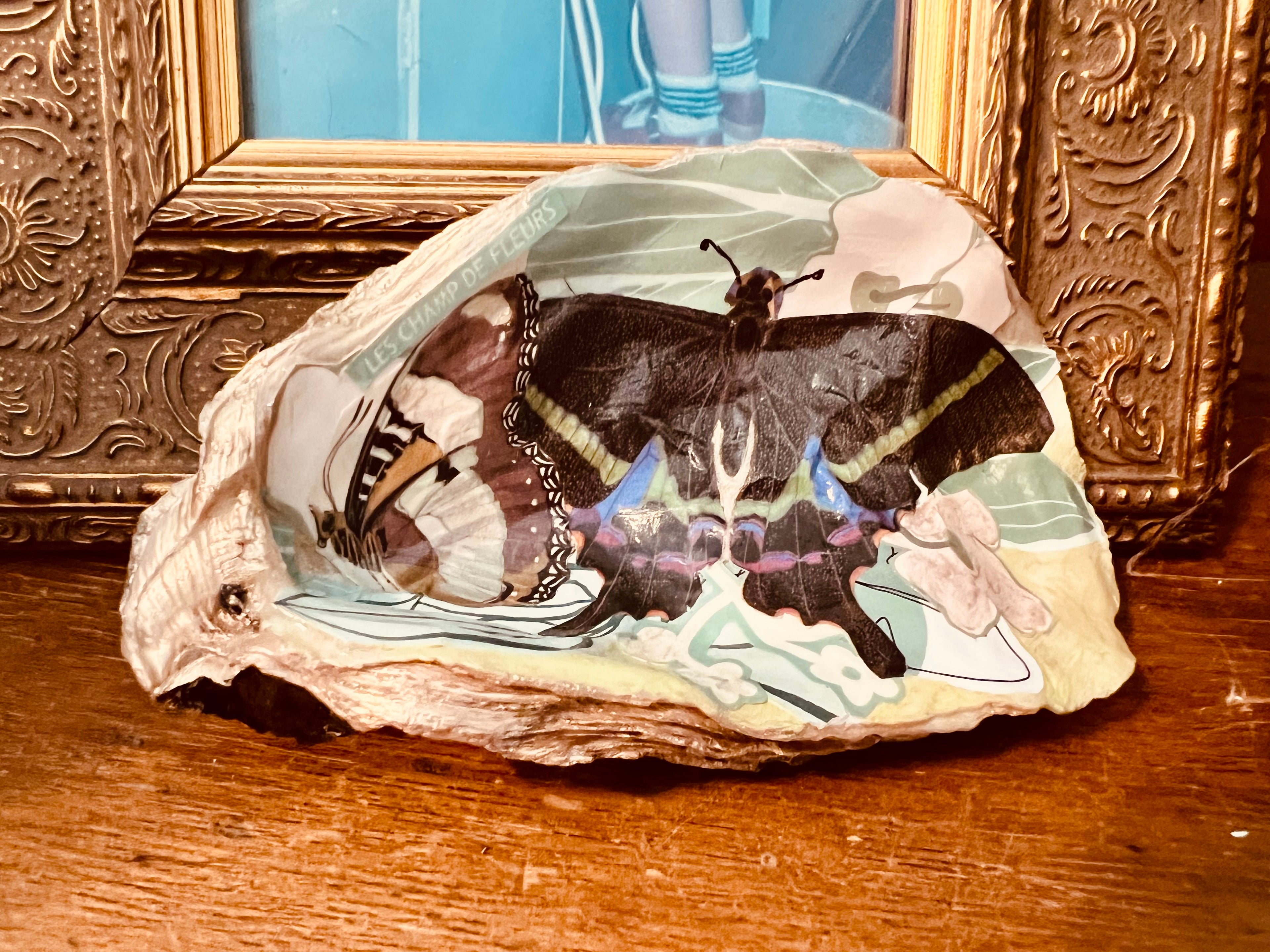 Handmade oyster shell trinket dish with floral and butterfly collage, champagne gold accents, and glossy sealed finish.