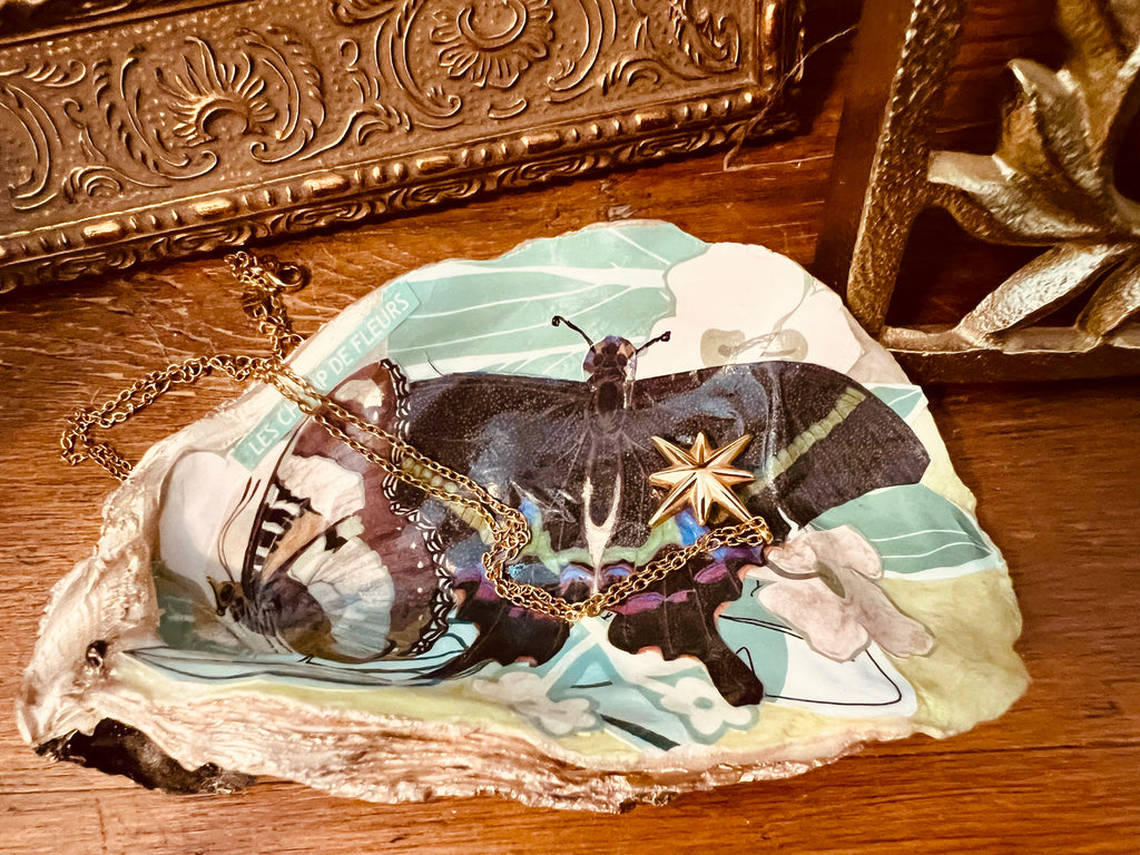 Oyster shell trinket dish with floral and butterfly collage, gold accents, and glossy finish, perfect for holding jewelry.
