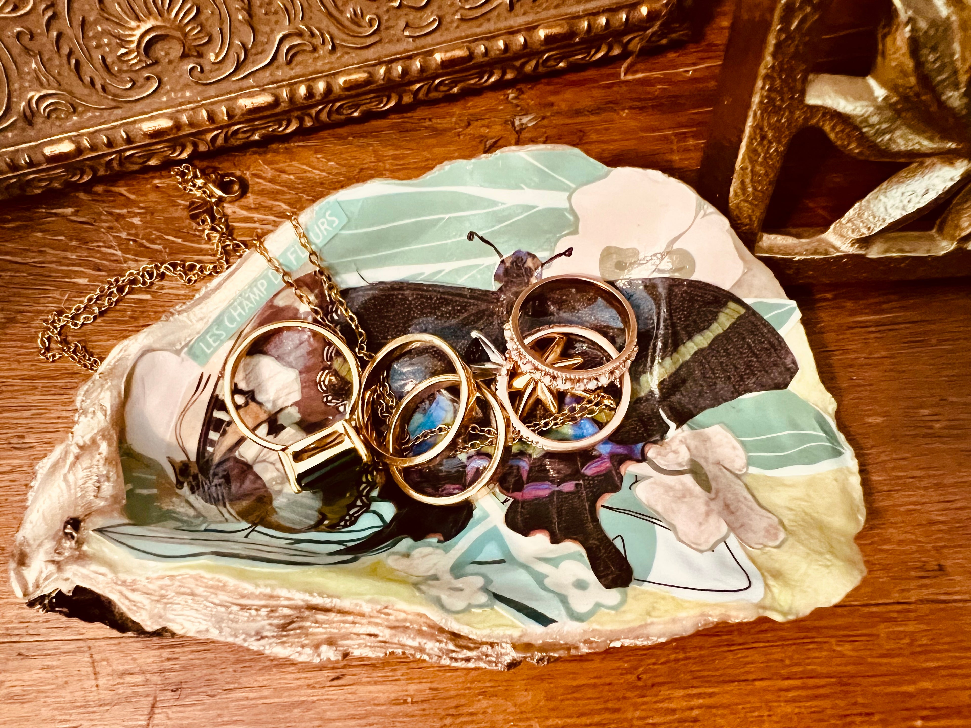 Handcrafted oyster shell dish featuring vintage postcard butterflies, floral details, and champagne gold, ideal for jewelry storage.