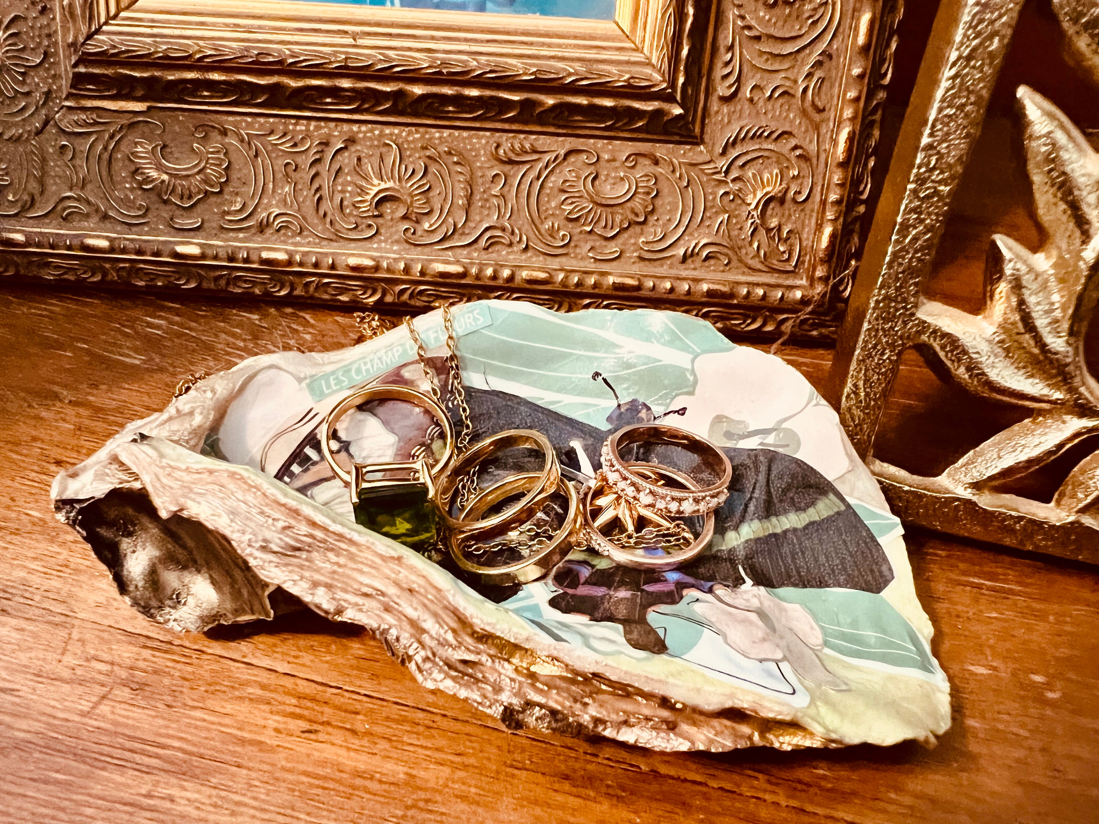Unique oyster shell jewelry holder with French paper stamp, green and gold accents, and recycled art details.