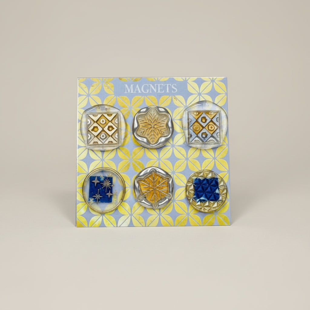 Set of six decorative magnets on a patterned card with 'Magnets' text, on a wooden surface.