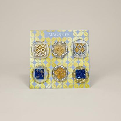 Set of six decorative magnets on a patterned card with 'Magnets' text, on a wooden surface.