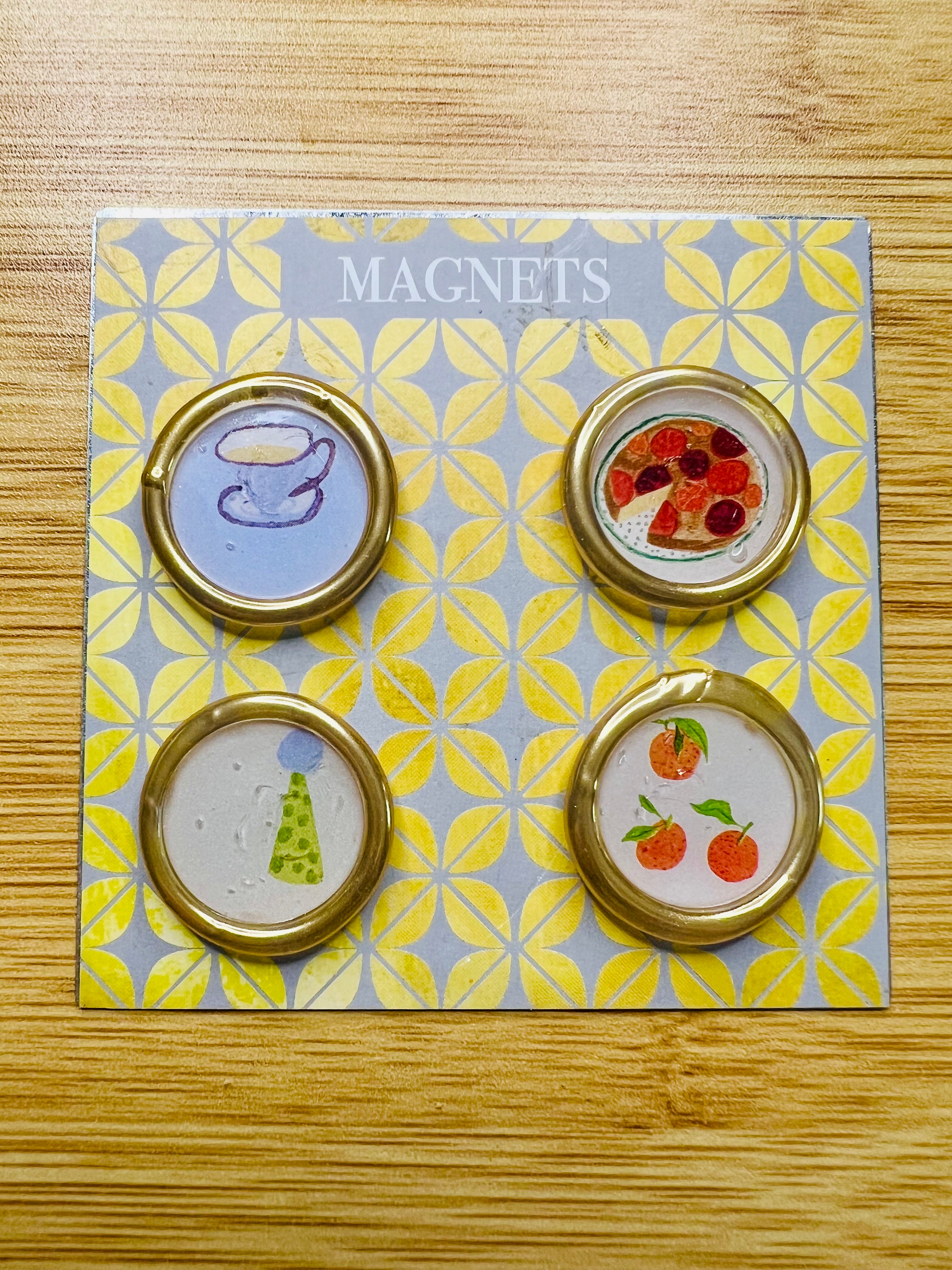 A set of handcrafted magnets by Rochambeau Home feature a tea cup, party hat, fruit tart, and tangerine wax seal magnets for fridge or office