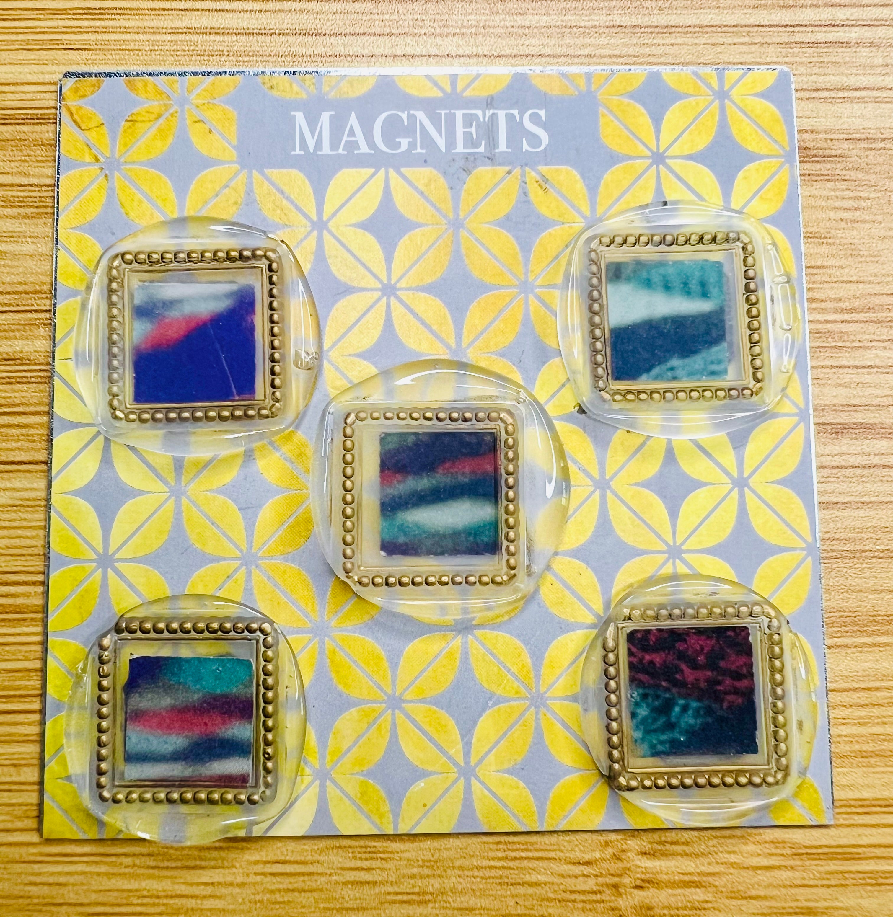 Set of colorful square wax seal magnets created by Rochambeau Home laid out on a 'Magnets' display 