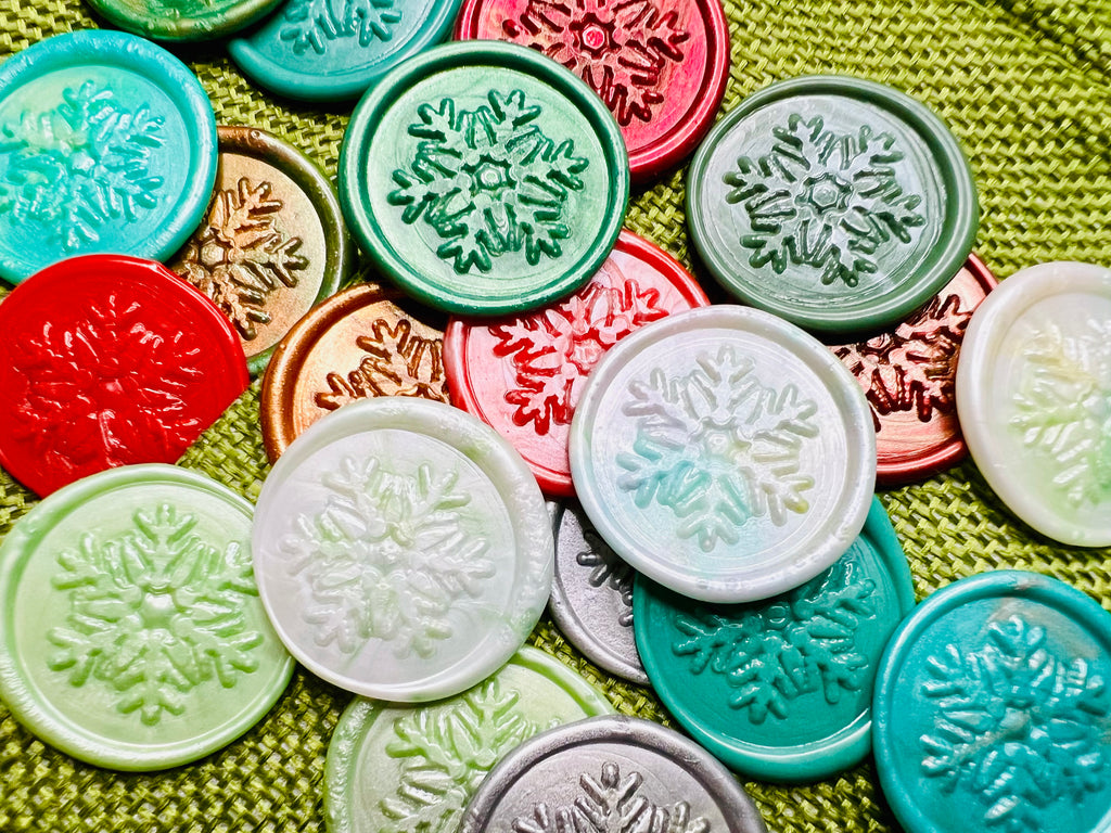 Close up view of Rochambeau Home snowflake wax seal stickers on a green burlap bag