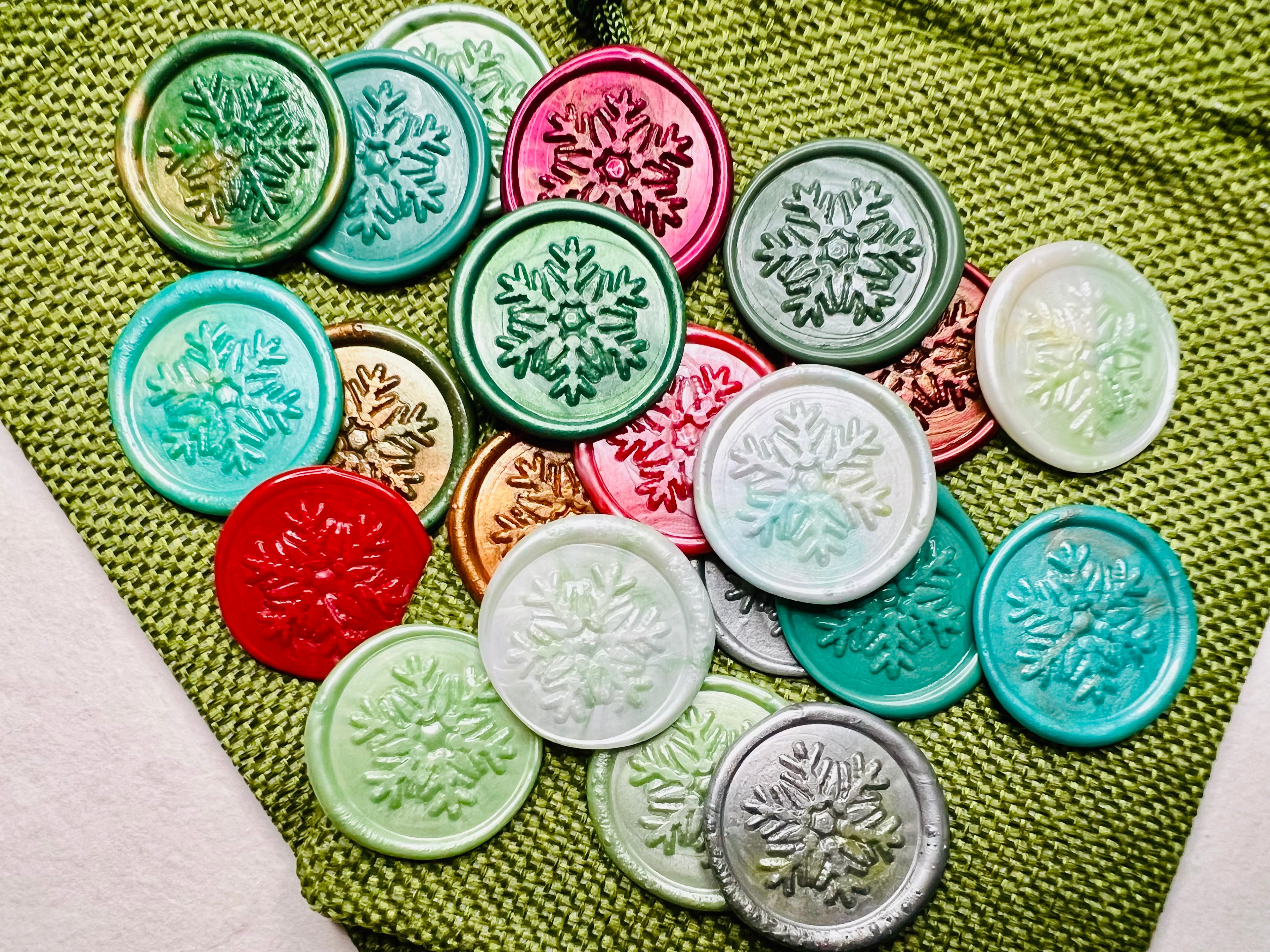 Festive snowflake wax seal stickers created by Rochambeau Home on a green burlap bag