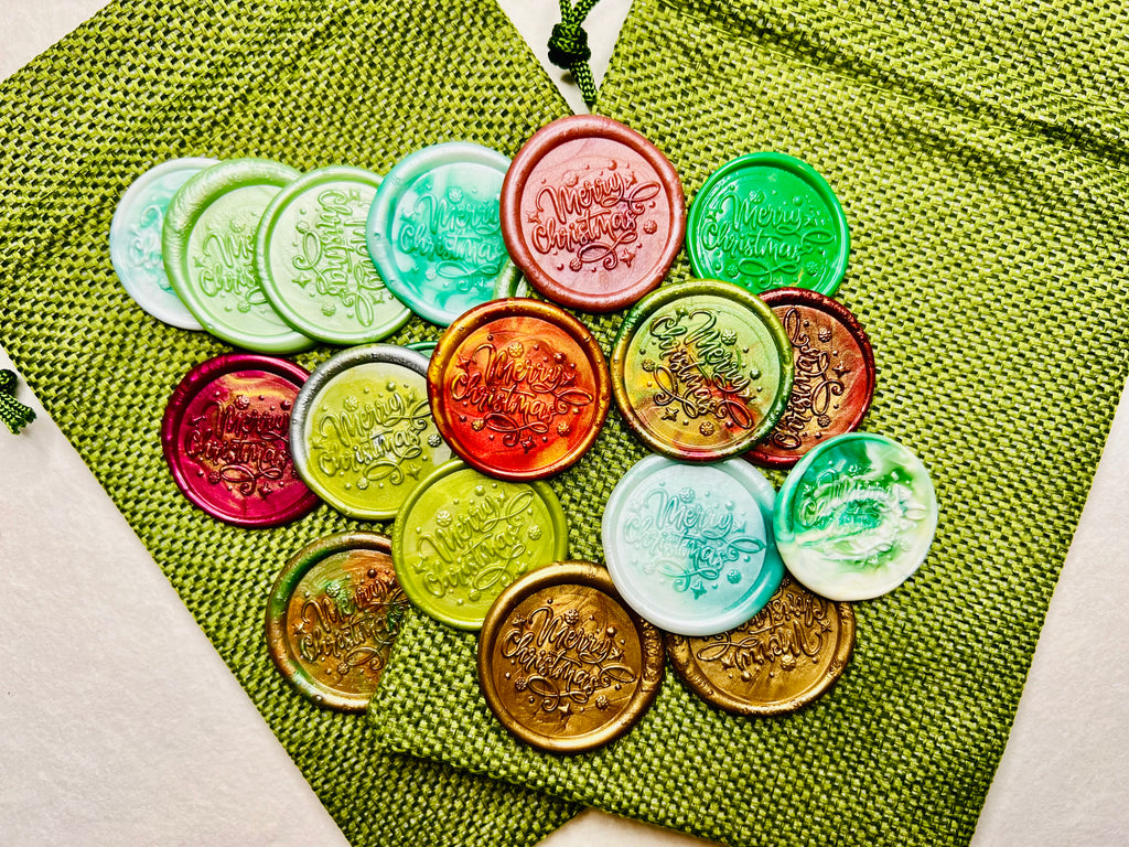 Colorful wax seal stickers with “Merry Christmas” embossed with tiny star details on two green burlap bags