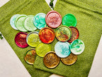 Colorful wax seal stickers with “Merry Christmas” embossed with tiny star details on two green burlap bags