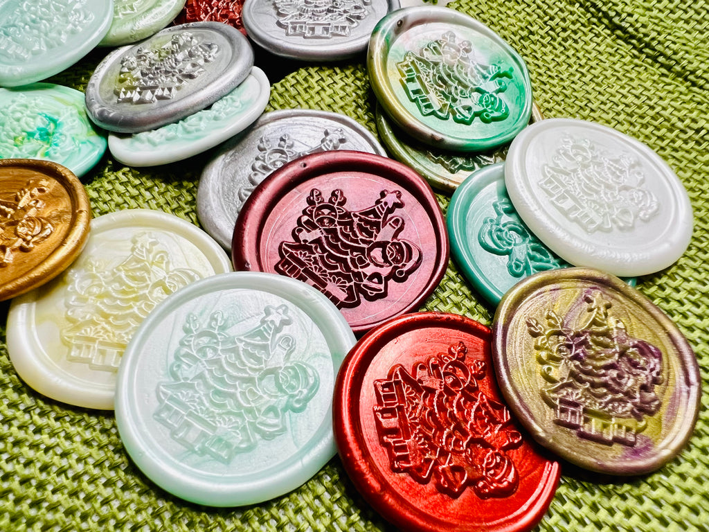 Close up view of the wax seal stickers with Santa beside a twinkling tree surrounded by wrapped gifts, in various colors.