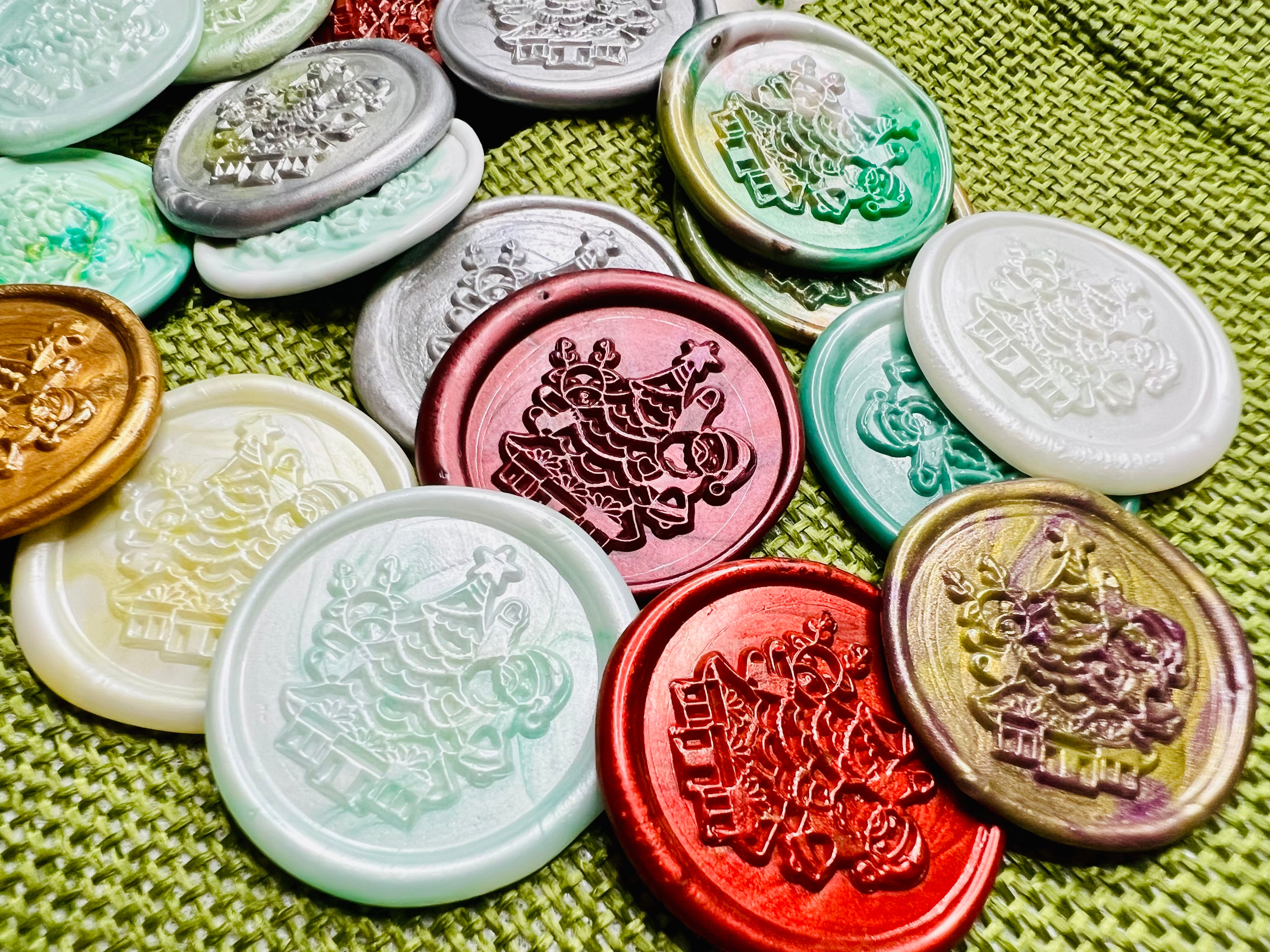 Close up view of the wax seal stickers with Santa beside a twinkling tree surrounded by wrapped gifts, in various colors.