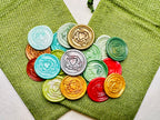 Holiday Heart in Hand wax seal stickers created by Rochambeau Home in various colors  being showcased on green burlap bags.