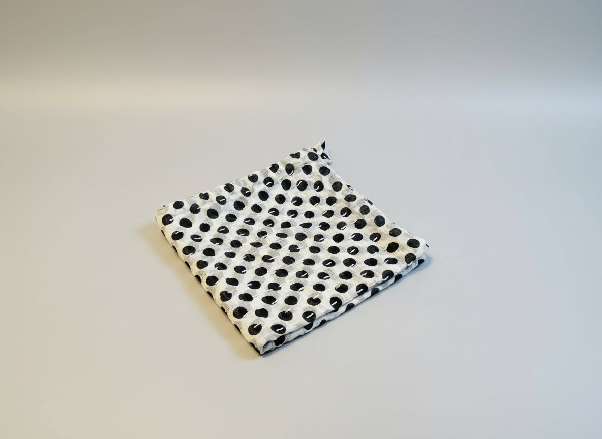 Black and white polka dot dish cloth on a gray background.