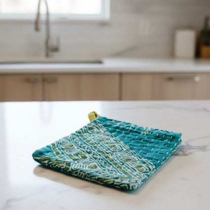 Teal fabric dish cloth with geometric pattern on a light gray background