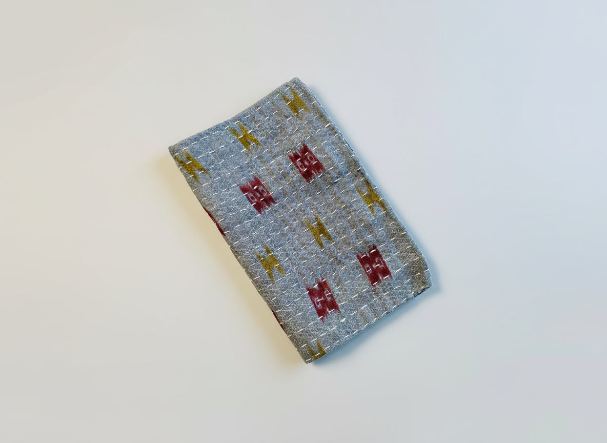 A textured, multicolored Kantha kitchen towel on a gray background. 