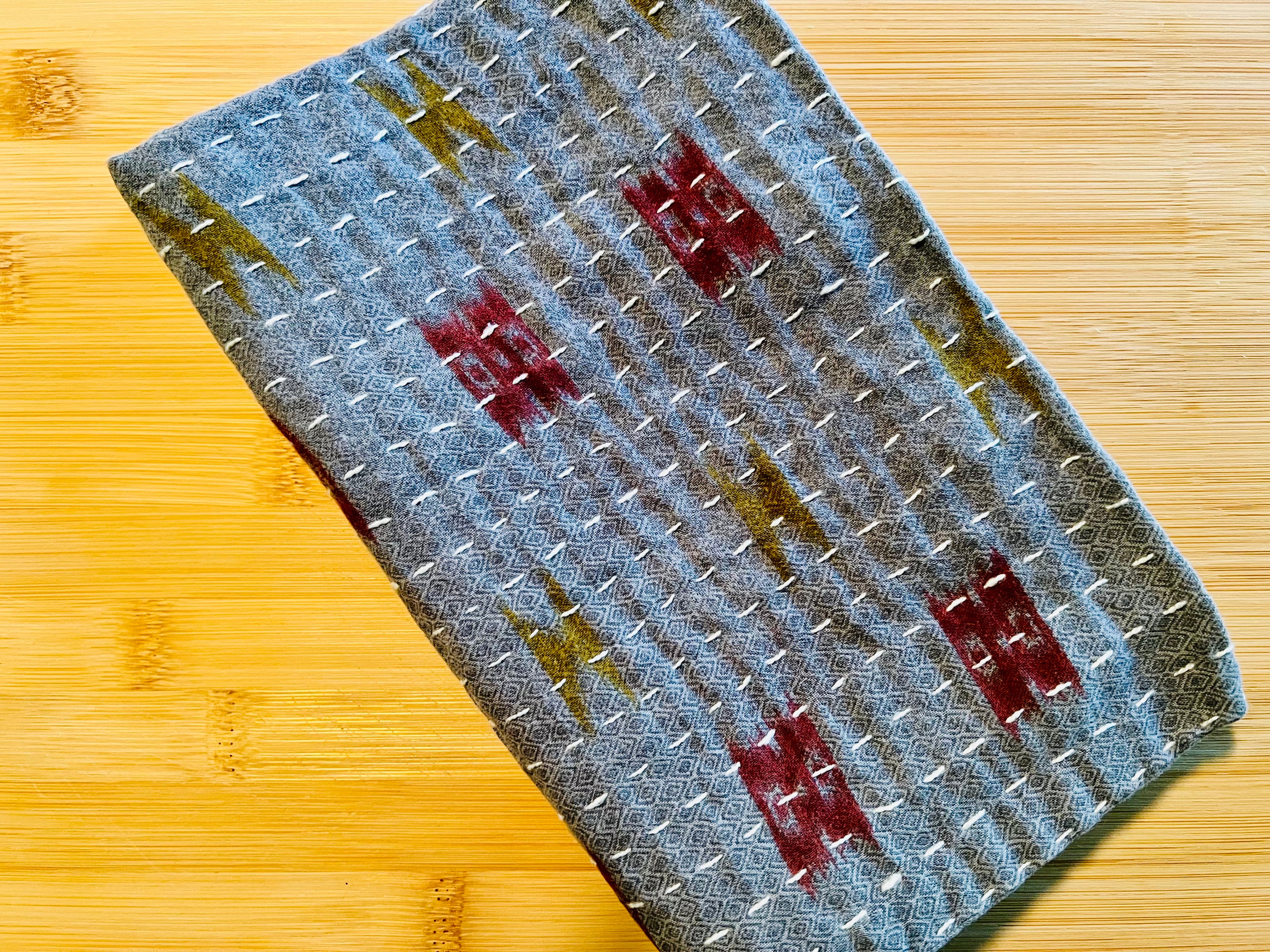 Textured blue fabric towel with red and gold patterns on a wooden surface