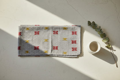 A textured, multicolored Kantha kitchen towel on a gray background. 
