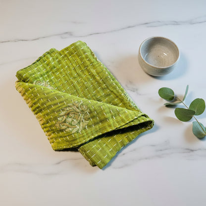 A soft green and floral patterned Kantha dish towel displayed on a neutral background.