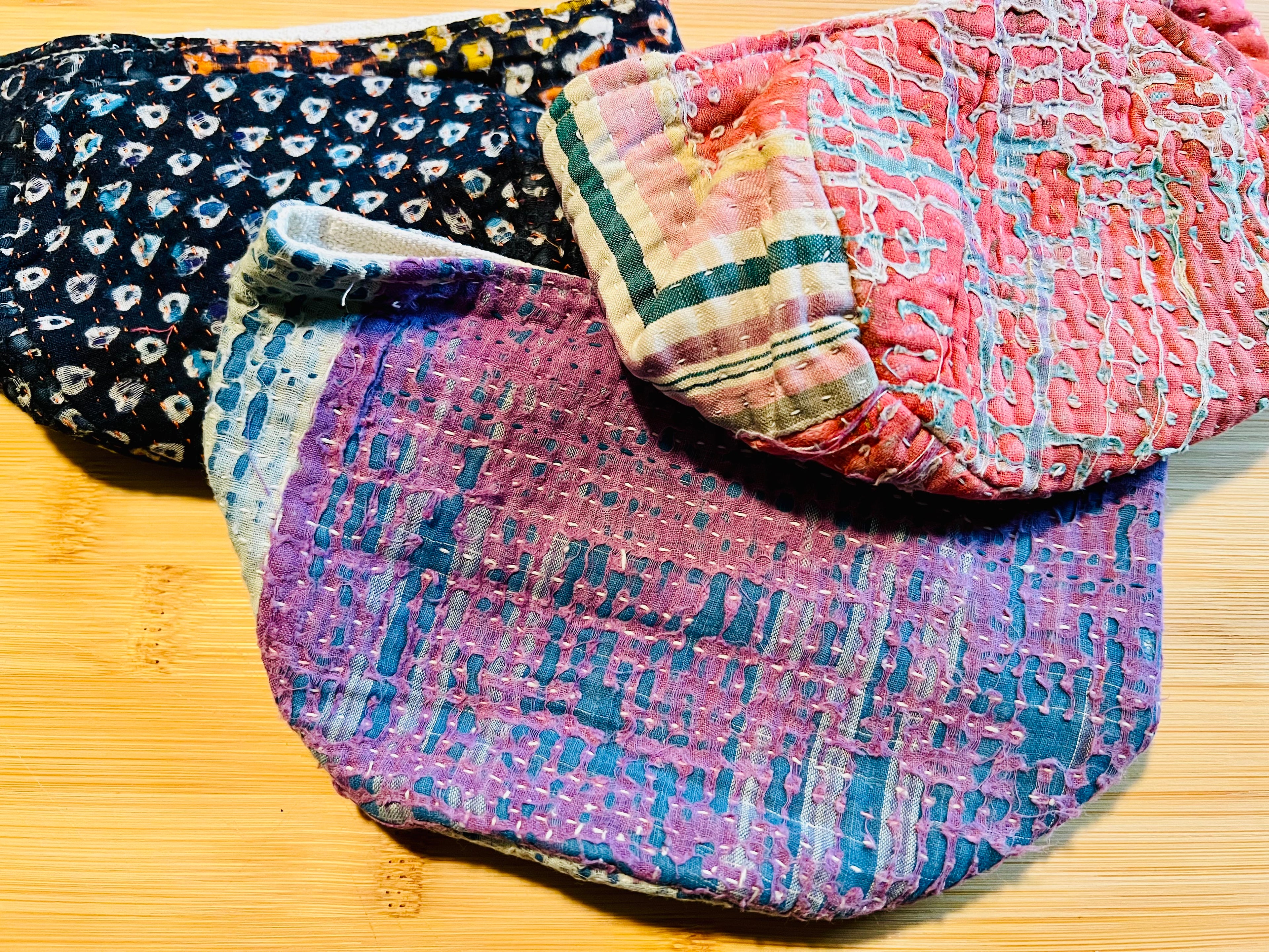 Three colorful fabric pouches on a wooden surface