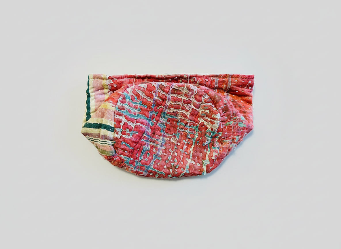 A colorful pink and green Kantha basket folded on a neutral background.