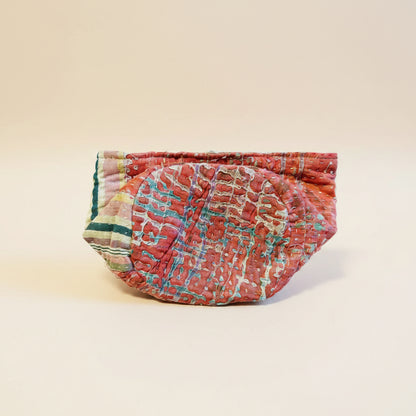 A colorful pink and green Kantha basket folded on a neutral background.