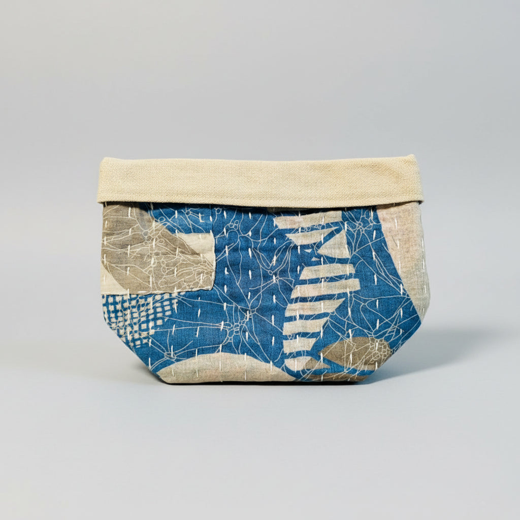 Kantha fabric basket in various blue and gray colors on a light background.