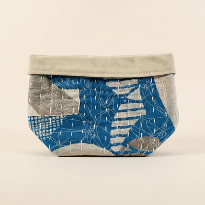 Kantha fabric basket in various blue and gray colors on a light background.