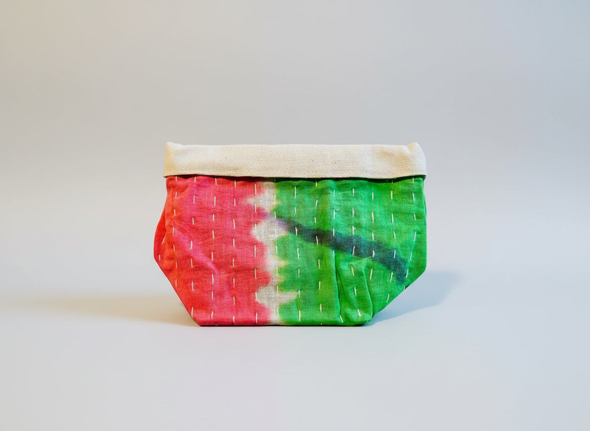 Kantha fabric basket in vibrant pink and green colors on a neutral background.