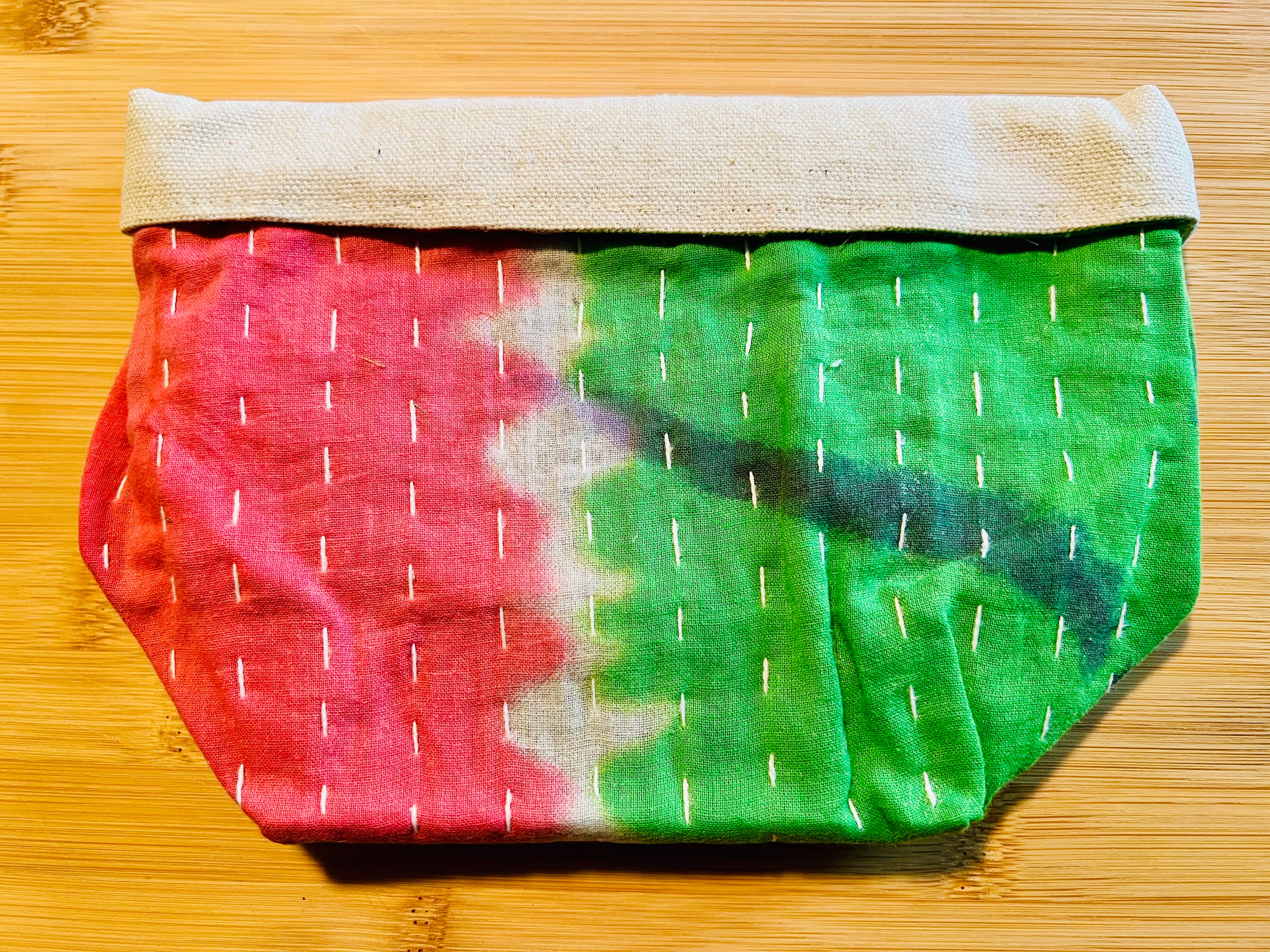 Fabric pouch with pink and green pattern on a wooden surface
