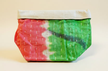 Kantha fabric basket in vibrant pink and green colors on a neutral background.