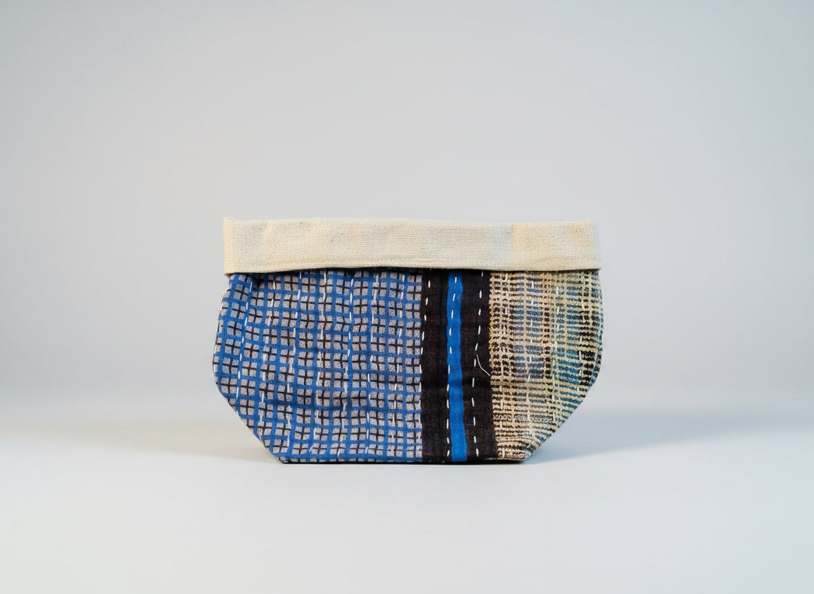 Geometric patterned black, blue, and white Kantha basket on a neutral background.