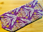 Purple fabric pouch with gold floral patterns on a wooden surface