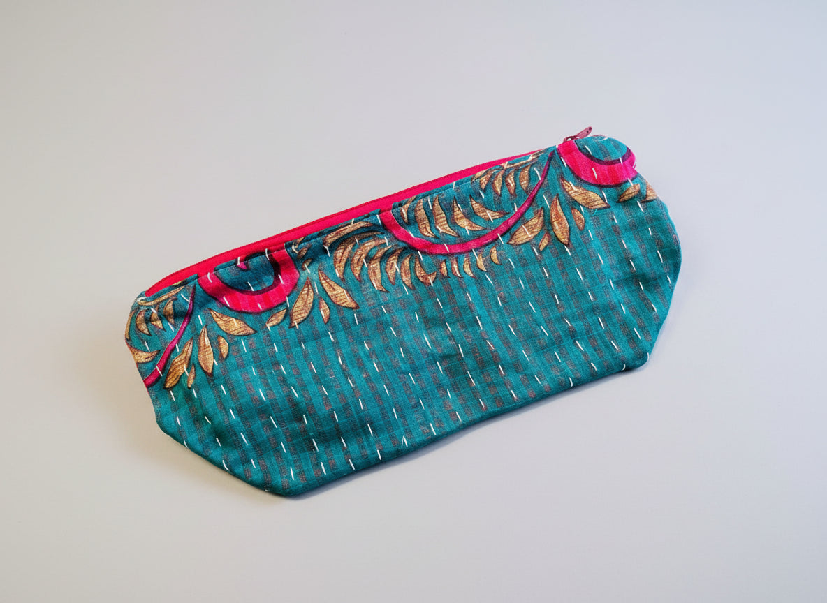A large zippered Kantha cosmetic bag with turquoise, pink, and yellow accents on a neutral background. 