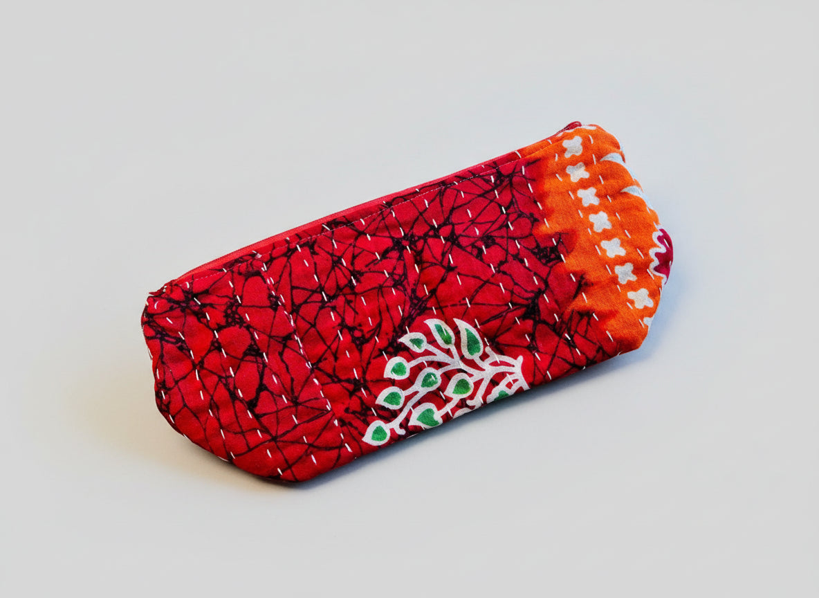 A large zippered Kantha cosmetic bag with red, green, and white geometric patterns.