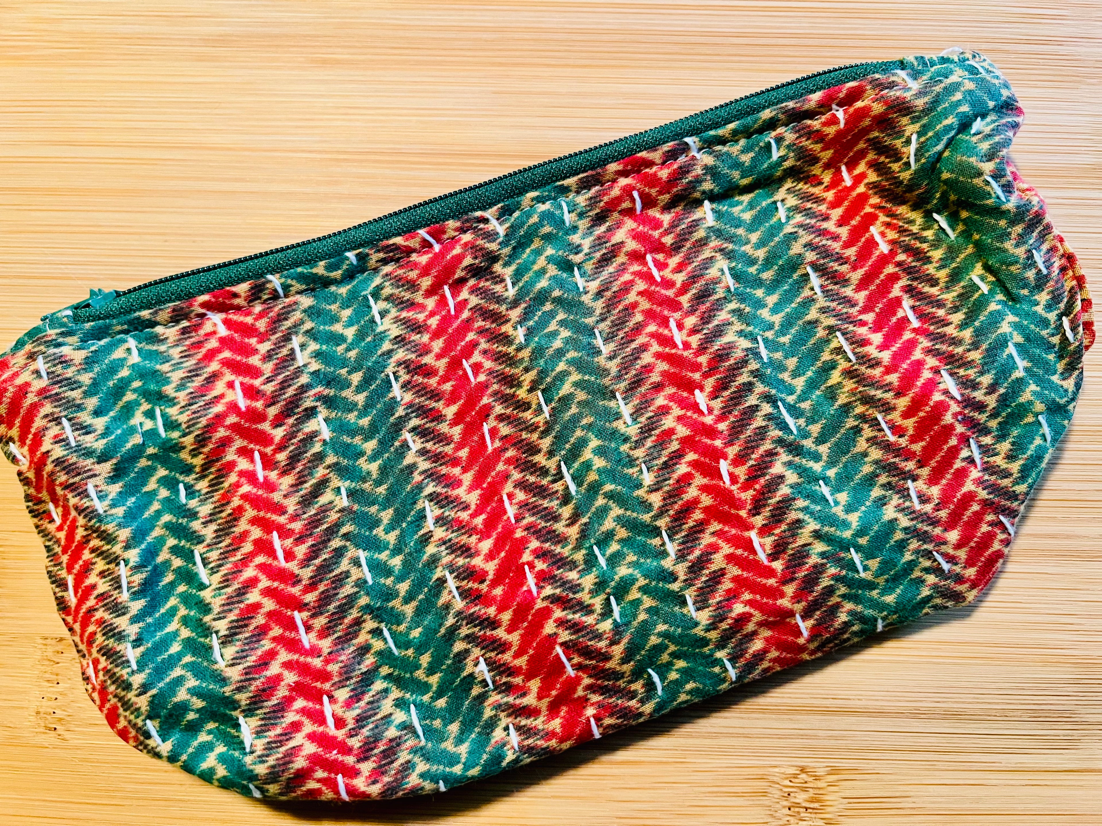 Colorful red and green patterned pouch on a wooden surface