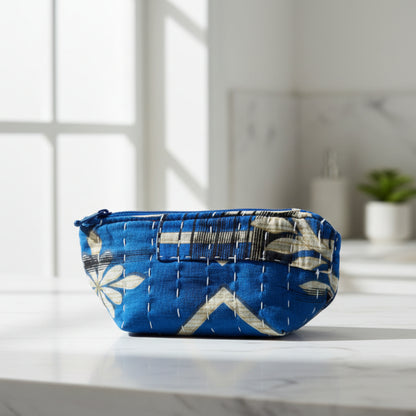 An abstract Kantha cosmetic bag with a blue and black floral design on a neutral background.