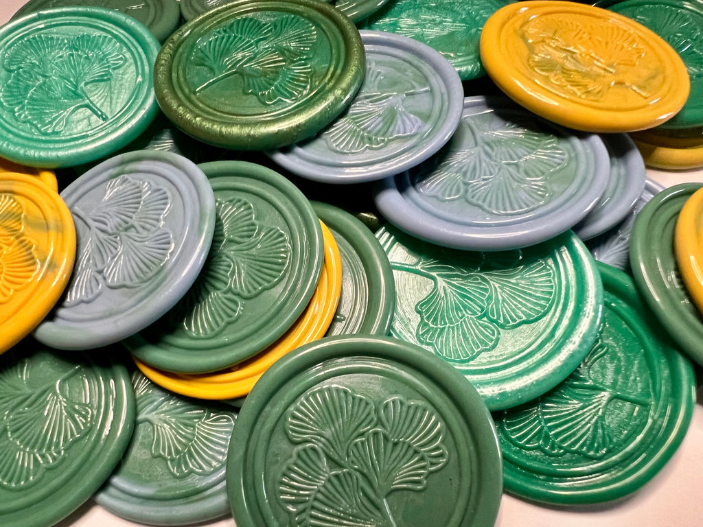Nature-inspired wax seal featuring a ginkgo leaf in golden yellow, green, and blue.
