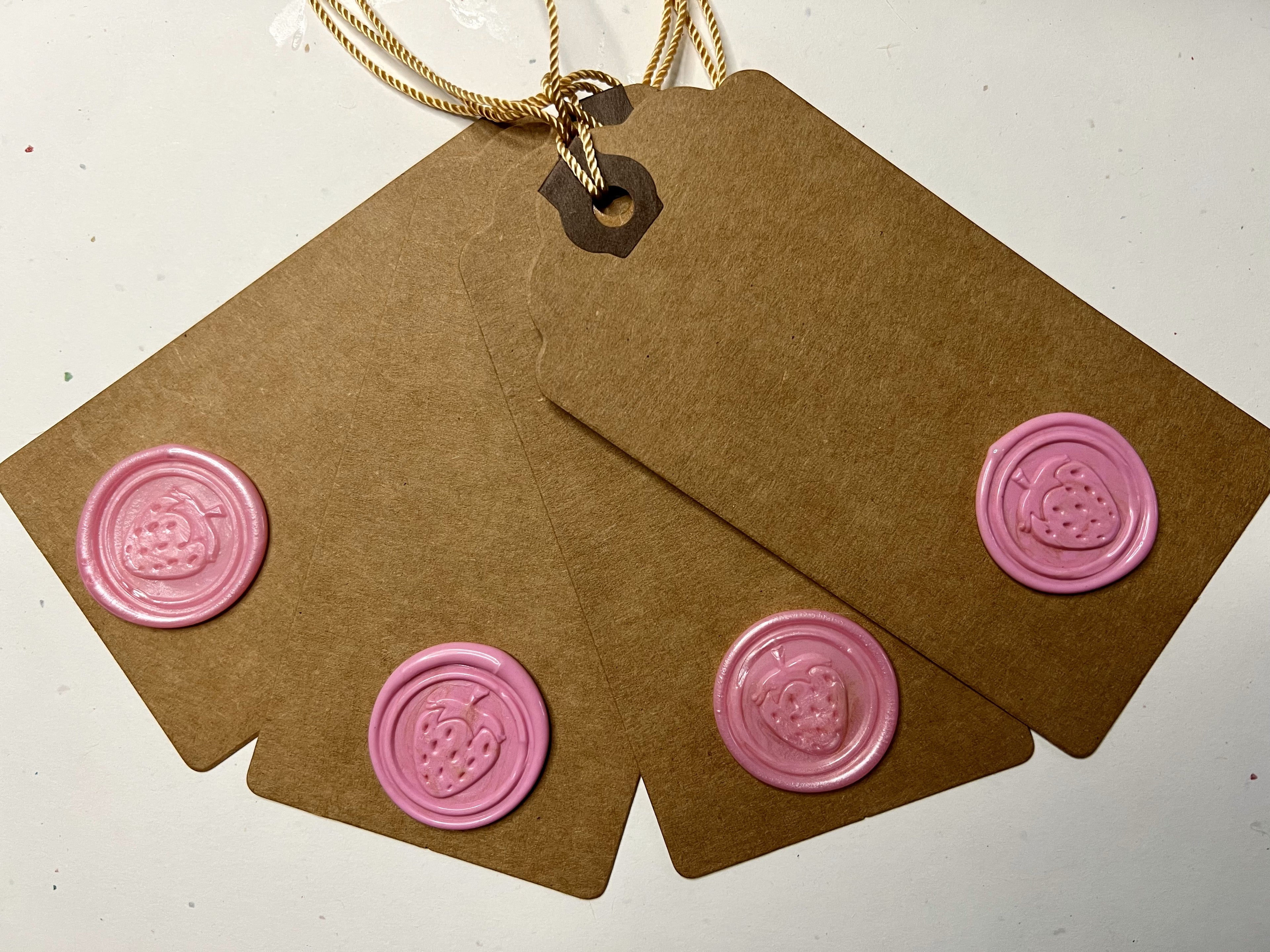Kraft paper gift tags with hand-poured strawberry wax seals, tied with rustic string.