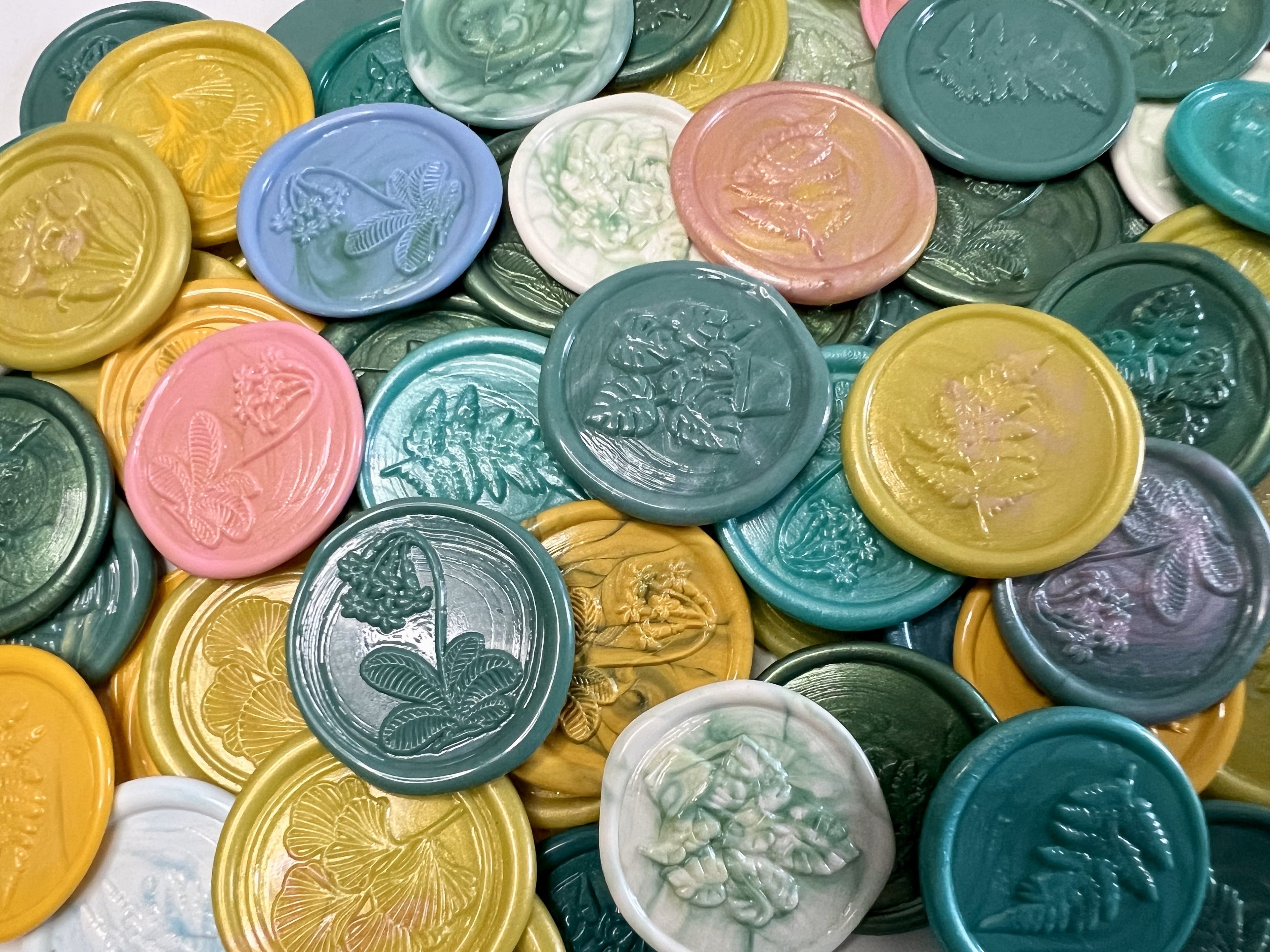 Garden-inspired wax seal stickers in shades of green, yellow, pink, and blue arranged on white stationery