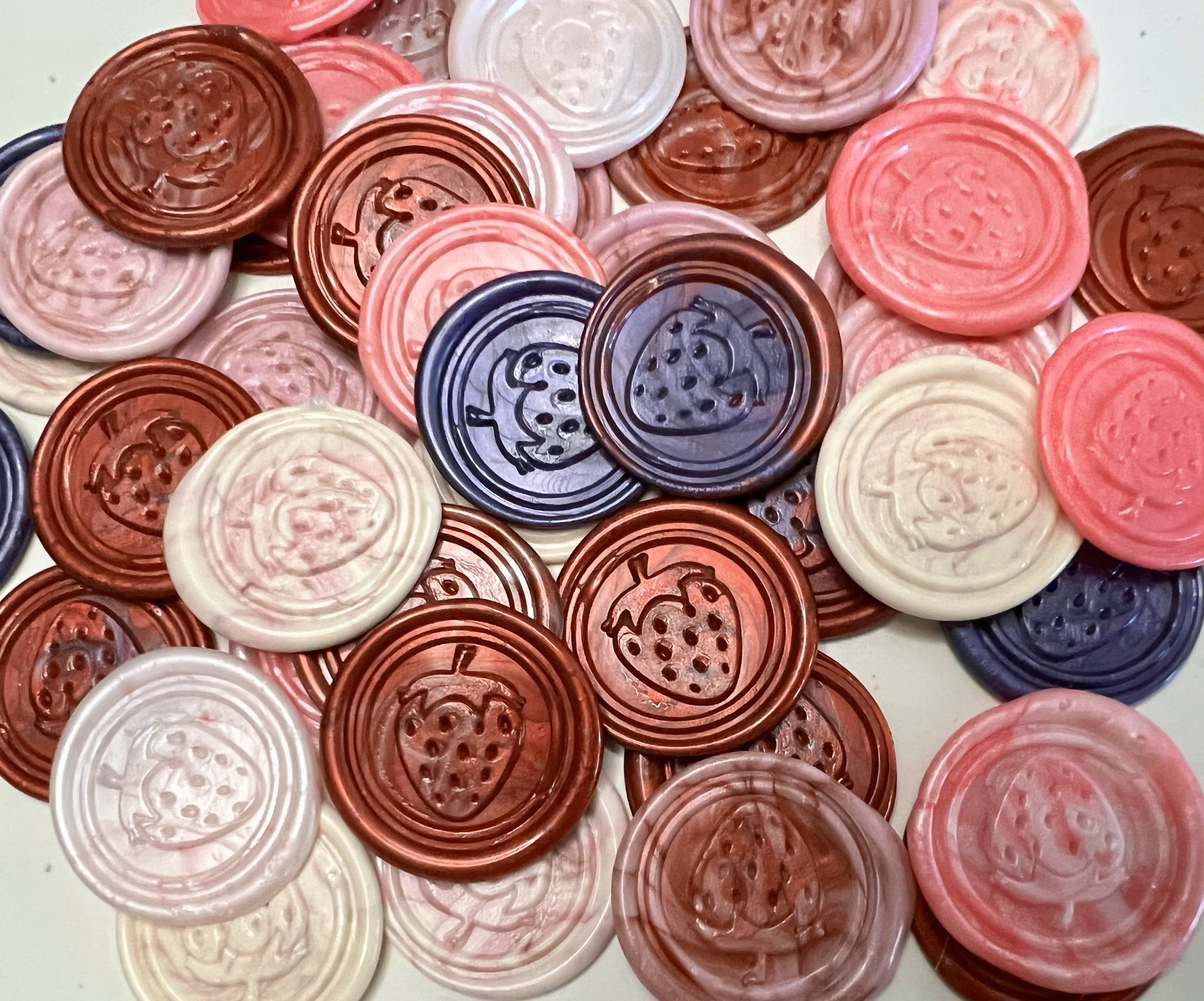 Playful wax seal featuring a juicy strawberry design in pink and red tones.