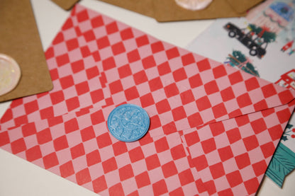 Close-up of "Merry Christmas" and Santa sleigh stamp on pink wax