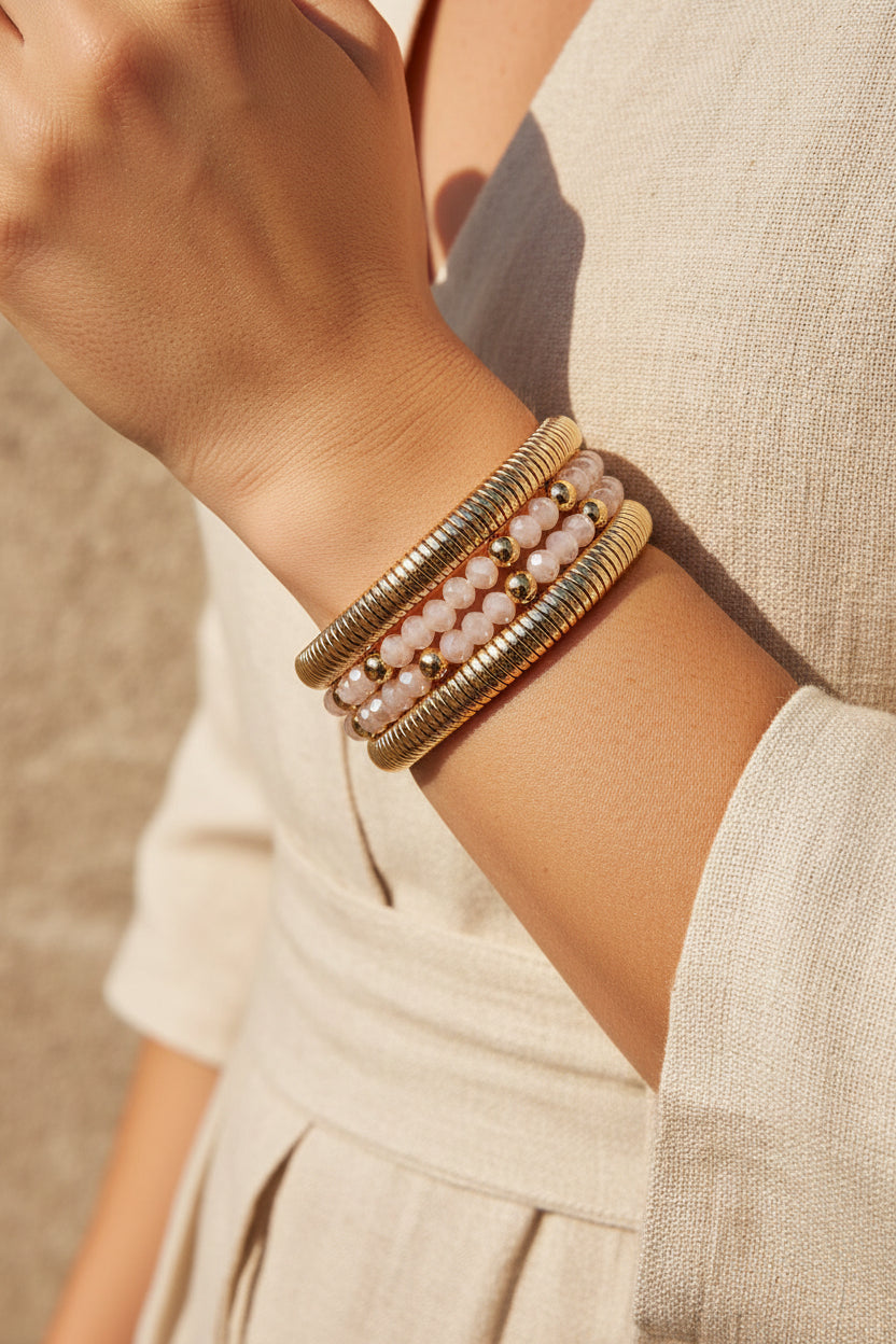 Set of gold and pearl beaded bracelets on a beige surface