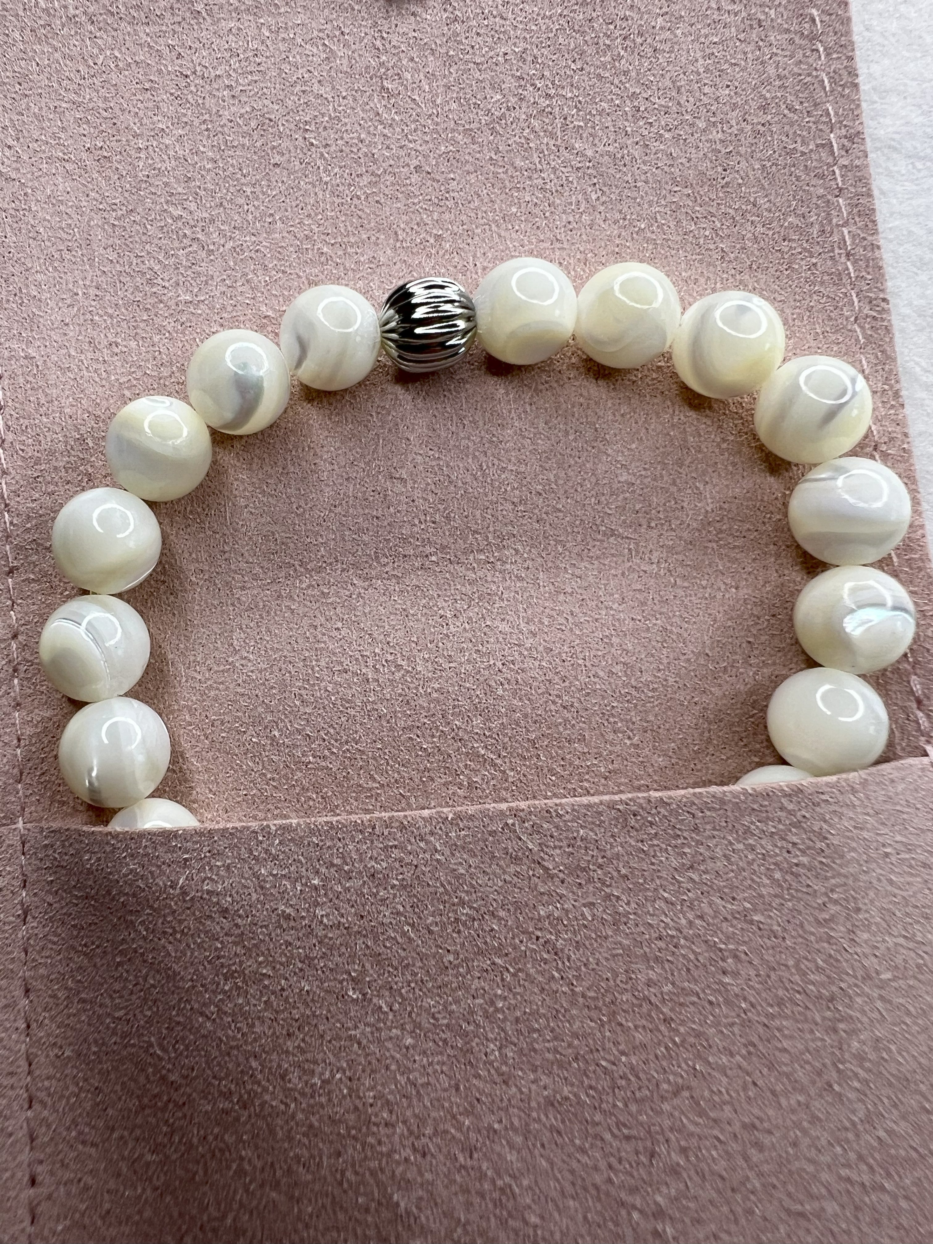 Mother of Pearl stretch bracelet with stainless steel beads shown on pink suede