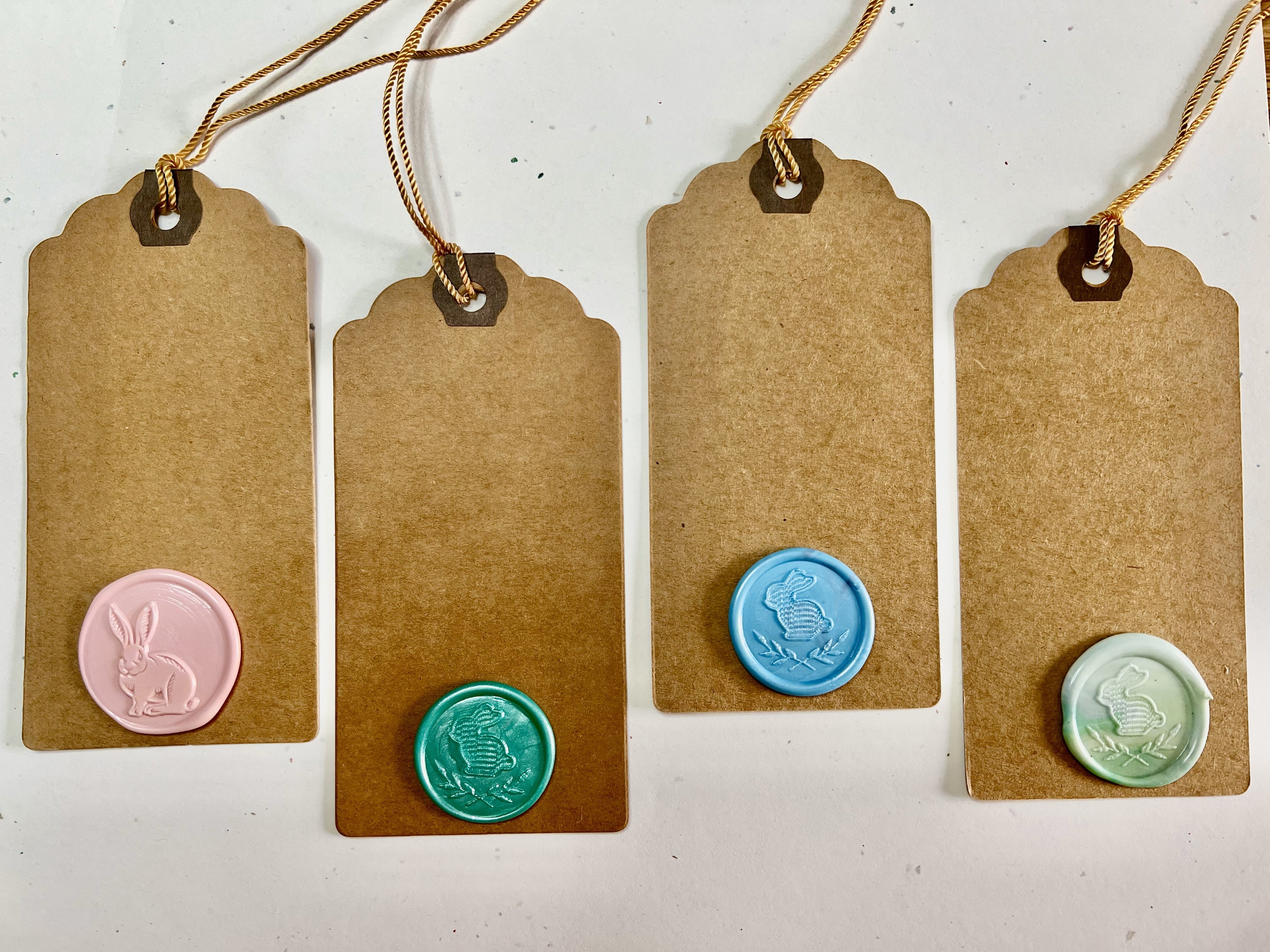Set of four Easter gift tags with pressed bunny and floral wax seals on kraft paper.
